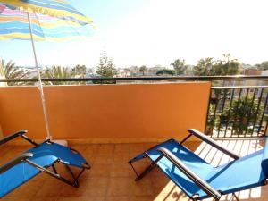 two blue chairs and an umbrella on a balcony at Apartamento Arcoiris, con piscina y junto a playa de Alcudia in Alcudia