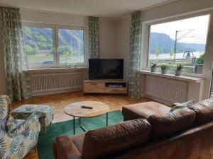 salon z kanapą i telewizorem z płaskim ekranem w obiekcie Rheingold w mieście Hirzenach