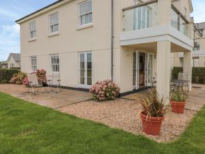 a white house with chairs and plants in the yard at 4 Thurlestone Beach House in Kingsbridge