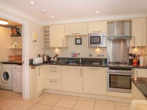 cocina con armarios blancos, lavadora y secadora en 4 Thurlestone Beach House, en Kingsbridge