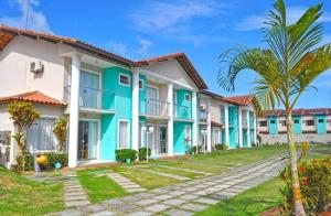 a row of houses with a palm tree in front at Casa 3 Suites Duplex AR Completa Condomínio fechado Moria à 500 m Praia Axe MOI in Porto Seguro