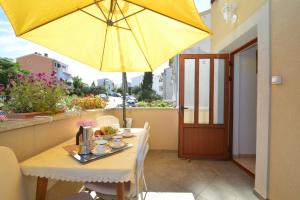 a table with a yellow umbrella on a balcony at House Orhideja in Mali Lošinj