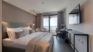 a hotel room with a large bed and a desk at Vivid Blue Serenity Resort in Sveti Stefan