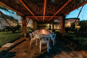 a long table with white chairs under a pergola at A Casa do Outeiro in Ribeira Grande