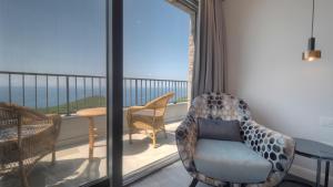 a room with a balcony with a chair and a table at Vivid Blue Serenity Resort in Sveti Stefan