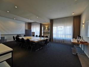 une salle de conférence avec une grande table et des chaises dans l'établissement Hotel Gutsmühle, à Obernburg am Main