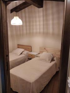 1 dormitorio con 2 camas y luz en Loboratorio Rural - La Majada del Acebo en Navatejares