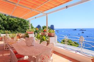 stół i krzesła na balkonie z widokiem na ocean w obiekcie Villa Teste di Moro w mieście Capri