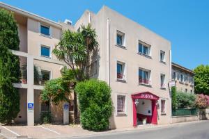 een wit gebouw met een palmboom naast een straat bij Hotel du Forum in Carpentras