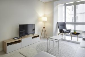uma sala de estar com televisão e duas cadeiras em Xingola - Basque Stay em San Sebastián