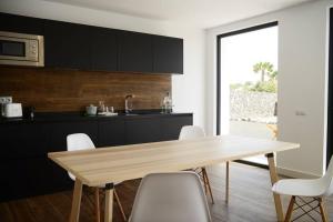 eine Küche mit einem Holztisch und weißen Stühlen in der Unterkunft Duna Colorada 4 in Lajares