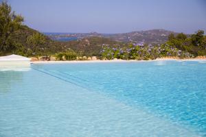 a pool of blue water next to a beach at Casagliana Suite Resort in Olbia