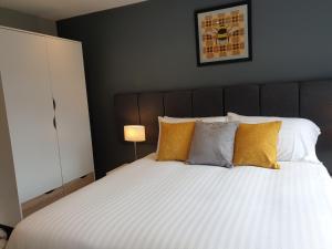 a bedroom with a large white bed with yellow pillows at The Spires Serviced Apartments Cardiff in Cardiff