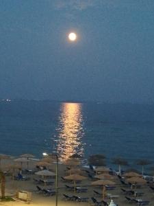 a full moon rising over a beach with umbrellas at STUDIO MARGARITA in Nea Plagia