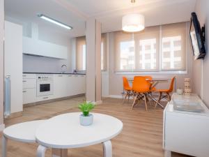 een keuken en eetkamer met een witte tafel en oranje stoelen bij Gestión de Alojamientos Apartments in Pamplona