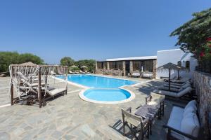 a swimming pool with lounge chairs and a resort at Parosland Hotel in Aliki
