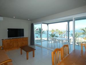 a living room with a television and a dining room with the ocean at Rentalmar Family Acantilados in Salou