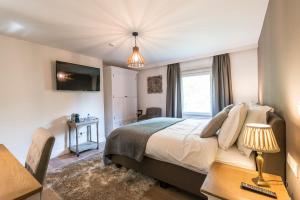 Dormitorio con cama, escritorio y TV en Charmehotel Klokkenhof en Brasschaat