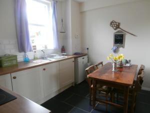 uma cozinha com uma mesa, um lavatório e uma janela em Valley View Cottage em Morebattle