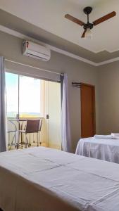 - une chambre avec un lit et un ventilateur de plafond dans l'établissement Pouso Oliveira Suítes, à São João Batista do Glória