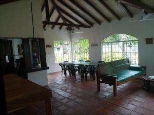 een eetkamer met een groene bank en tafels en ramen bij La Ceja Beach House in El Tamarindo