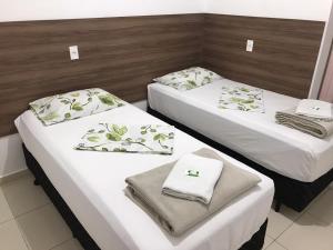 two beds in a hotel room with towels on them at Hotel Jardim Emilia Sorocaba in Sorocaba