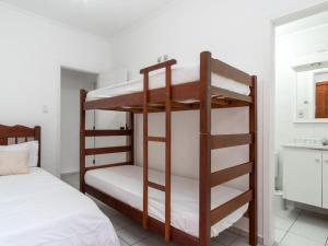 two bunk beds in a room with a kitchen at Apartamento espaçoso com ar condicionado e Wi-fi, a 100 metros da praia - Edifício Estoril in Ubatuba