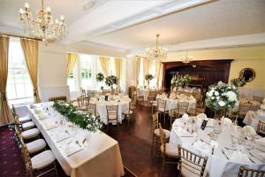 ウッドホール・スパにあるWoodhall Spa Manor - Stylish Secret Escapeの白いテーブルと椅子、シャンデリアが備わる宴会場