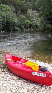 una canoa roja sentada a orillas de un río en hotel la Ribera, en Santianes