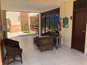 a patio with wicker chairs and a table and a door at Flat Condominio Dunnas XXI in Aquiraz