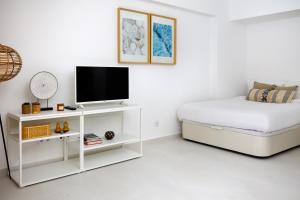 a white bedroom with a bed and a tv at Sesimbra Beach House by Saudade in Sesimbra