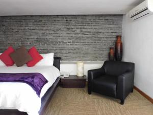 um quarto com uma cama e uma cadeira preta em Hotel & Spa Luna Canela Boutique em Atlixco