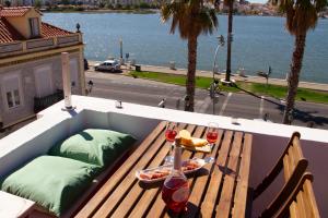 a bench on a balcony with a table with food and wine at Seixal Bay Apartments in Arrentela