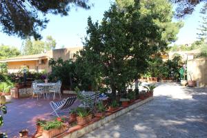 a patio with a table and chairs and trees at CASA AL MARE A SCOPELLO in Scopello