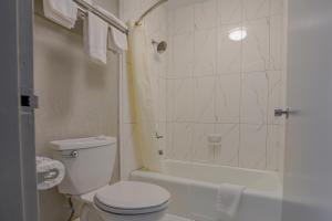 a white bathroom with a toilet and a shower at Executive Inn Locust Grove in Locust Grove