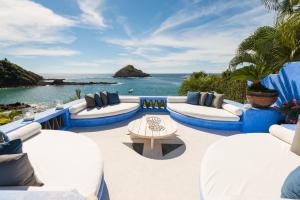 um pátio com mobiliário branco e azul e o oceano em Casa Azul & Casa Carioca in Careyes em Careyes
