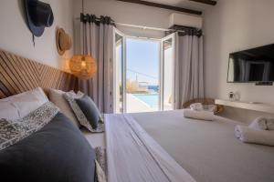 a bedroom with a large bed and a large window at SeaCode Villas in Platis Yialos Mykonos