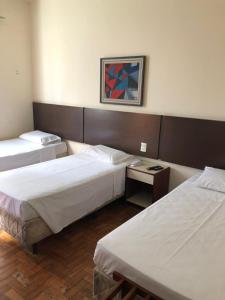 a hotel room with two beds and a television at Brasil Palace Hotel in Belo Horizonte
