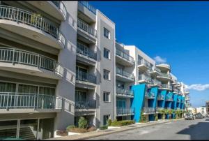 a large apartment building with blue balconies on a street at Hillock Residence Gozo Marsalforn in Marsalforn