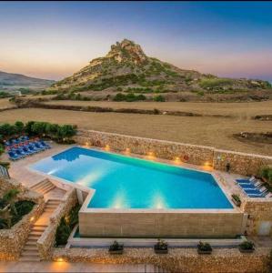 a swimming pool with a mountain in the background at Hillock Residence Gozo Marsalforn in Marsalforn