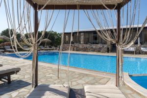 a resort pool with chairs and an umbrella at Parosland Hotel in Aliki
