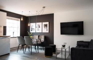 ein Wohnzimmer mit einem Tisch, Stühlen und einem TV in der Unterkunft Golden Key Apartments in Lillington