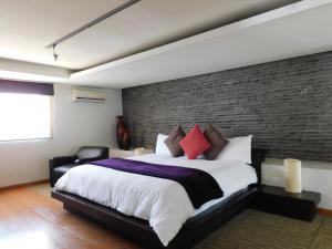 um quarto com uma cama grande e uma parede de tijolos em Hotel & Spa Luna Canela Boutique em Atlixco