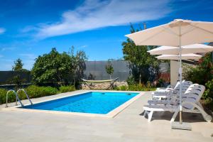 una piscina con sillas blancas y sombrilla en Holiday House Emma, en Burići