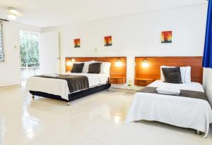 two beds in a large room with white floors at Hotel Thama in Palmira