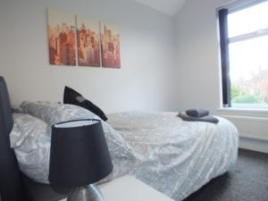 een slaapkamer met een bed met een lamp en een raam bij Stamford Place by SG Property Group in Crewe