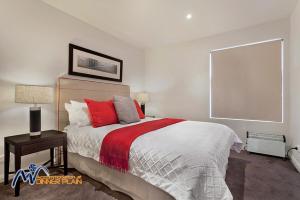 a white bedroom with a large bed with red pillows at Zoncolan in Dinner Plain