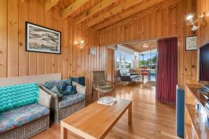 een woonkamer met een bank en een tafel bij Queenie - Waikanae Beach Holiday Home in Waikanae