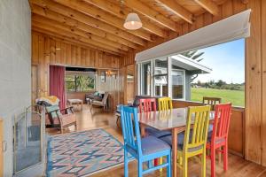 een eetkamer met een tafel en kleurrijke stoelen bij Queenie - Waikanae Beach Holiday Home in Waikanae