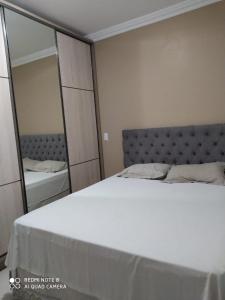 1 dormitorio con cama blanca y espejo en Apto Jairo e Eliane com 03 quartos e garagem interna en São José